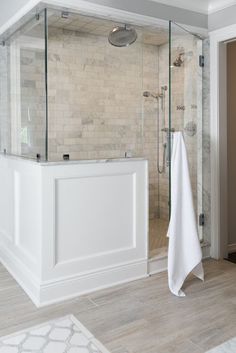 a bathroom with a glass shower door and white towels hanging on the wall next to it