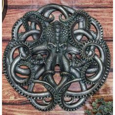 an intricately designed metal object on a wooden surface with succulents around it