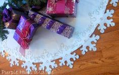 presents are wrapped in purple and red paper on a doily with snowflakes