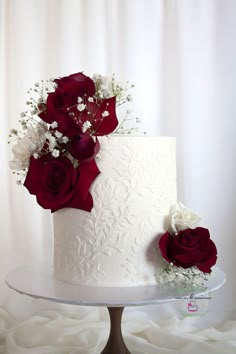 a white cake with red roses on top