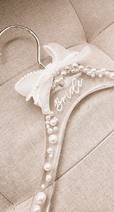 a wedding dress hanger with pearls and the word sorry written on it's side