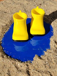 two yellow shoes sitting on top of a blue puddle