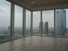 an empty room with wooden floors and large windows overlooking cityscape in the distance