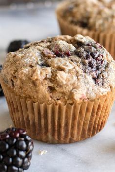 some muffins are sitting on a table with blackberries