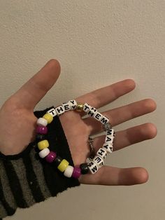 a person's hand wearing two bracelets with words written on them and beads