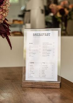 a menu sitting on top of a wooden table next to a vase filled with flowers