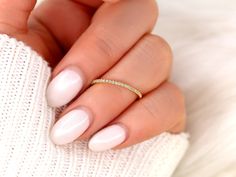 a woman's hand with white nails and a gold ring