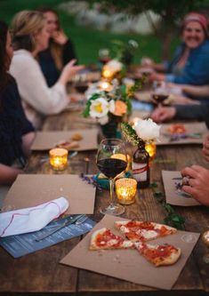 a group of people sitting around a table with pizzas and wine glasses on it