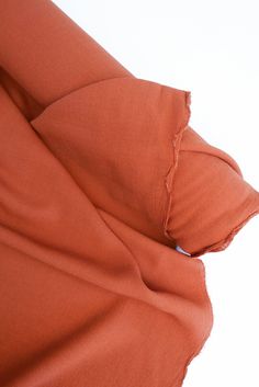 an orange sheet is laying on top of a white surface with the sheets pulled back