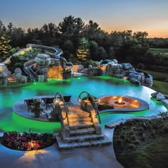 an outdoor swimming pool at dusk with steps leading up to the water slide and waterfall