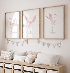 three flamingos are hanging on the wall above a bench with pillows and other items