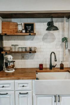 a kitchen with white cabinets and wooden counter tops is pictured in this image, there are shelves on the wall above the sink