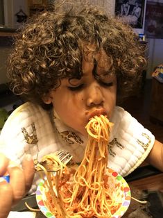 a young child eating spaghetti from a plate