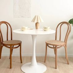 two chairs and a table in a room with white walls, wood floors and wooden flooring