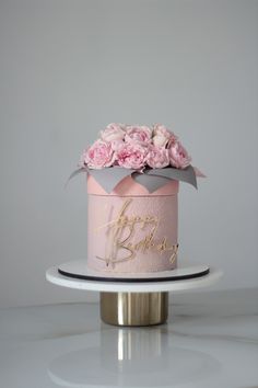 a pink and silver birthday cake with flowers on top