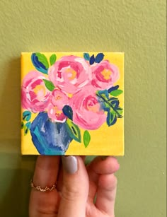 a painting of pink roses in a blue vase on a yellow background with green leaves