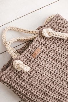 a crocheted bag sitting on top of a wooden floor next to a white wall