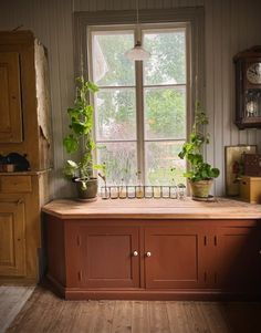 a kitchen with wooden cabinets and plants on the window sill in front of it