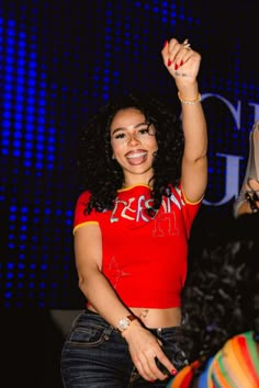 a woman in a red shirt is holding her fist up