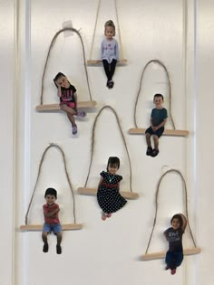 several children are sitting on swings hanging from the wall