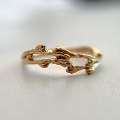 a gold ring with two branches on it sitting on a white surface, in front of a blurry background