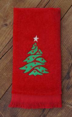 a red towel with a green christmas tree on it sitting on top of a wooden floor