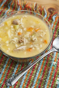 a glass bowl filled with soup on top of a colorful table cloth next to a spoon