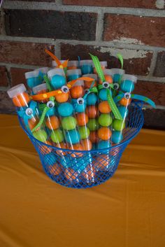 a blue basket filled with candy covered in orange, green and blue frosted candies