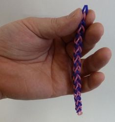 a hand holding a small purple and pink piece of string with one end in the middle