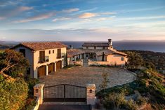 an aerial view of a large home on a hill overlooking the ocean and hills in the distance