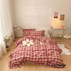 a bed with red and white checkered comforter on it in a bedroom next to a window