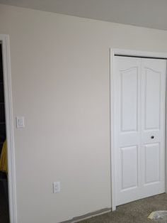 an empty room with two white doors and carpet on the floor in front of it