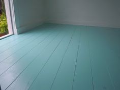 an empty room with blue painted floors and white paint on the floor is seen from outside