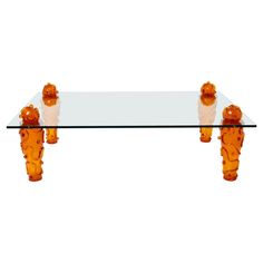 a glass table topped with two orange teddy bears sitting on top of it's legs