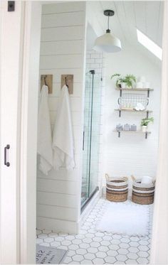 a bathroom with white walls and flooring, two towels hanging on the rack above the shower