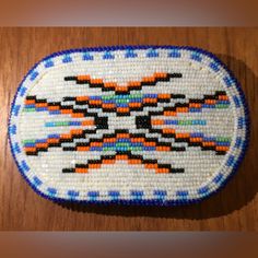 a beaded brooch sitting on top of a wooden table