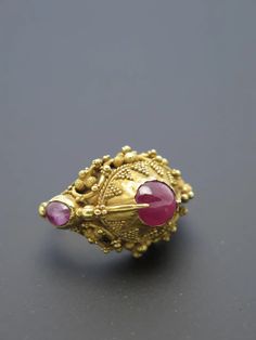 For Sale on 1stDibs - Finely worked in high karat gold (22k+) and featuring three rough cut ruby cabochons ranging form light pink to purplish pink, typical of rubies from Indonesia. Traditional Yellow Gold Ruby Ring, Traditional Ruby Ring In Yellow Gold, Gold Oval Ruby Ring With Three Stones, Gold Ruby Ring With Three Stones, Oval Shaped, Yellow Gold Gemstone Temple Ring, Yellow Gold Gemstone Temple Jewelry Ring, Yellow Gold Gemstone Ring In Temple Jewelry Style, Yellow Gold Temple Jewelry Ring With Gemstone, Traditional Yellow Gold Ruby Ring With Gemstone