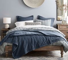 a bed with blue comforter and pillows in a bedroom next to a wall clock