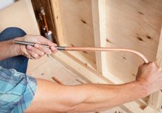 a man is working on an unfinished piece of wood with a pipe in his hand