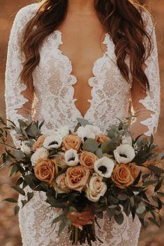 a woman holding a bouquet of flowers in her hands and wearing a wedding dress with long sleeves