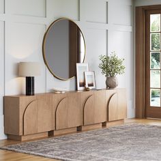 a living room with a large mirror on the wall next to a wooden cabinet and rug