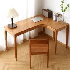 a wooden desk with a laptop on top of it next to a chair and lamp