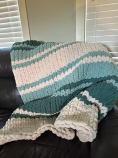 a blanket that is sitting on top of a leather couch in front of a window