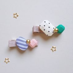 two small hair clips with bows and stars around them on a white tablecloth background