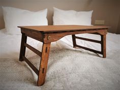 a wooden table sitting on top of a bed