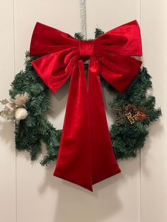 a christmas wreath with a red bow hanging on the front door