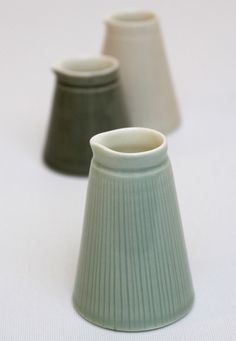 three small vases sitting on top of a white table next to eachother