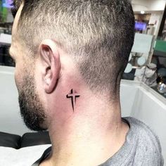 a man with a small cross tattoo on his left side behind the ear is looking at something