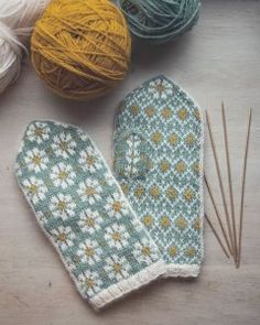 several balls of yarn and two mitts on a table with knitting needles next to them