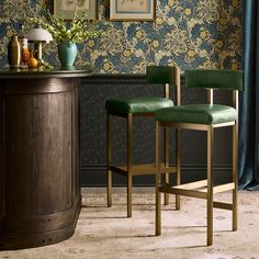 two green velvet bar stools in front of a floral wallpapered dining room